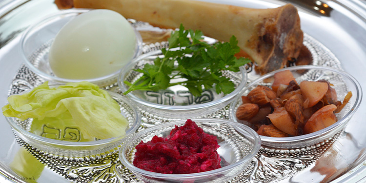 A silver seder plate with nuts, parsley, egg, lettuce, and more on it.