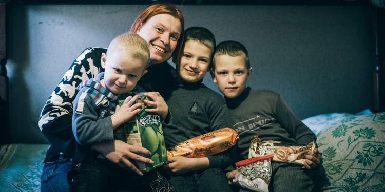Alexandra Shabanov with her three sons sitting on a bed.
