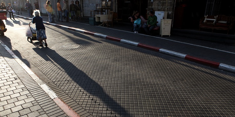 Elderly woman in street white hair walking with cart.