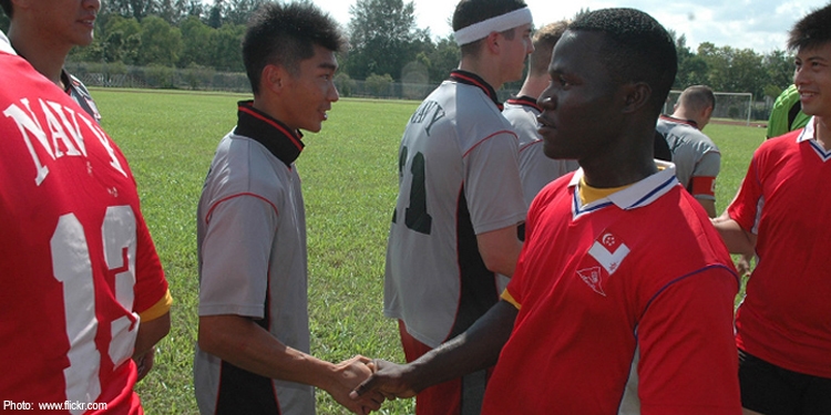 Soccer players in red and gray shaking each other's hands.