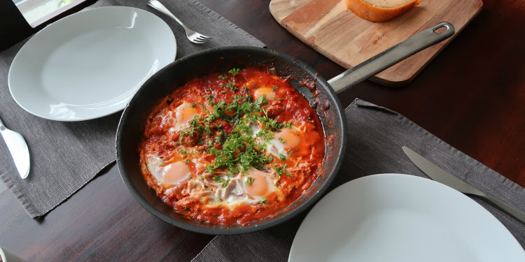 Shakshouka on a pan in between two table settings.