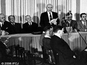 Black and white image of men signing a declaration. 