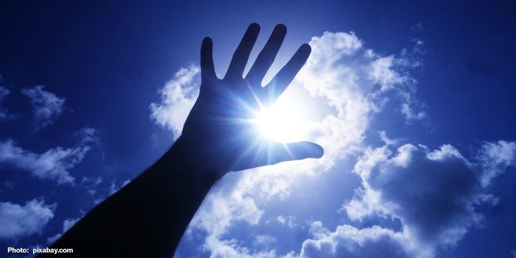 Hand reaching up with a cloudy blue sky behind it.