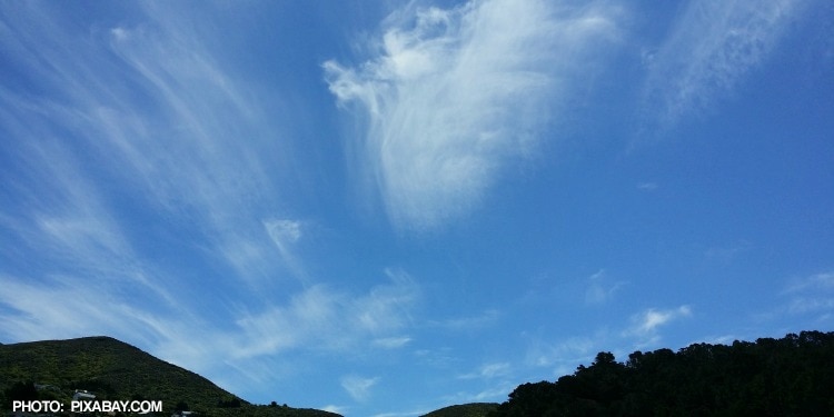 Mountains, trees, and an almost clear blue sky.