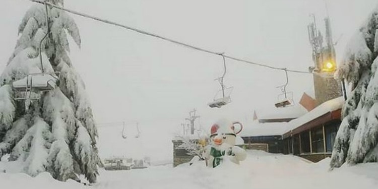 Snowy ski lift, trees, and building in Israel.