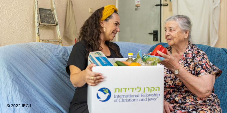 ael Eckstein and elderly woman sit on couch food box.