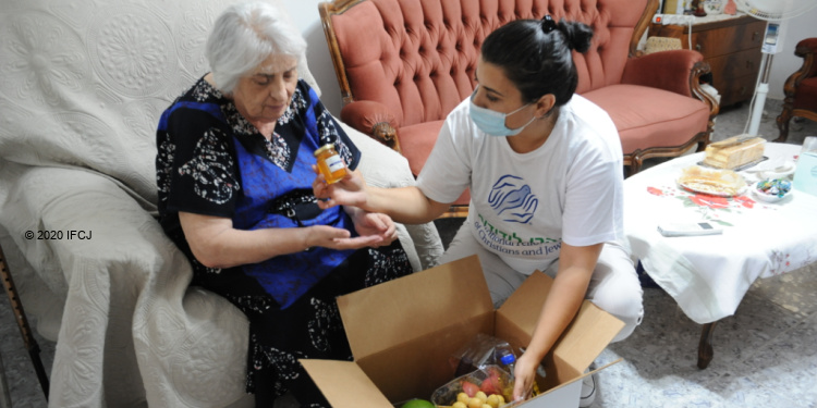 IFCJ staff member helping Yasmin Kalfa unpack her food box.