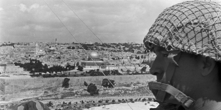 Black and white image of a soldier in Jerusalem looking off into the distance.