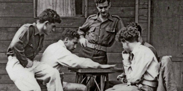 Black and white image of several men playing a game on a table.