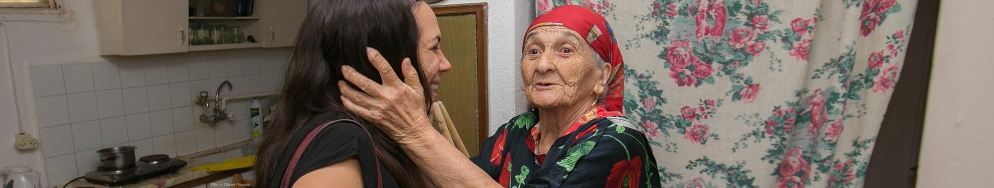 Elderly Jewish woman smiling and holding Yael's face while Yael is smiling.