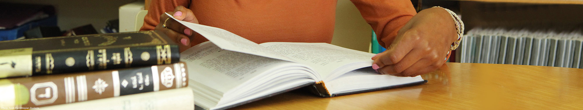 Woman flipping through books of scripture.