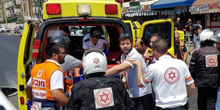 Eight ambulance medics helping a person on a stretcher into an ambulance van.