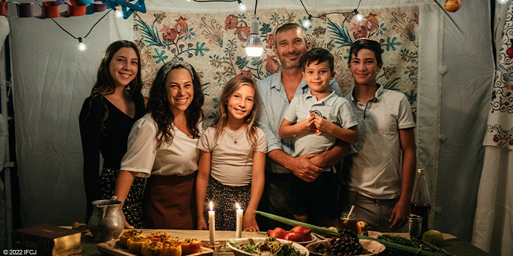 The Eckstein family stands inside a Sukkah smiling.