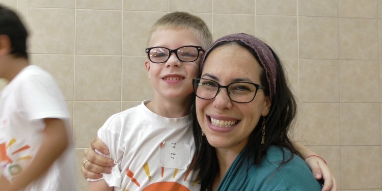 Yael Eckstein smiling with a young boy at Sunrise Israel Day Camp.