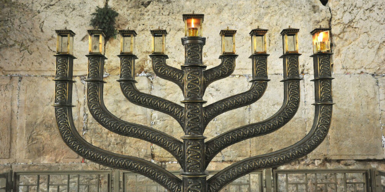 Large menorah against a brick wall.