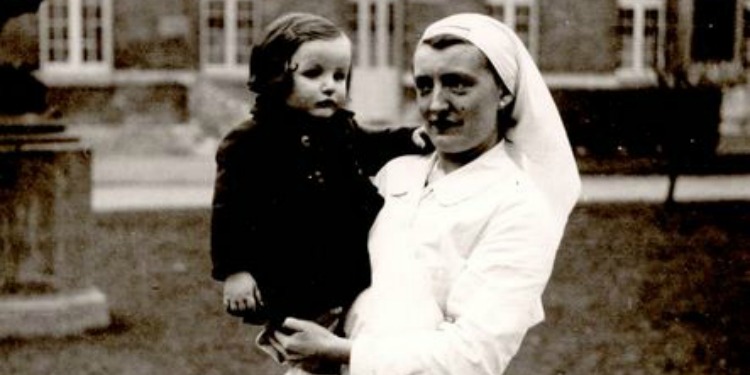 Dated image of a nurse holding a small child.