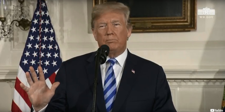 President Trump giving a speech with the American flag behind him.