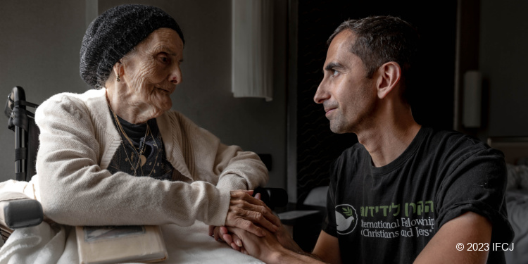 IFCJ volunteer holding hands with survivor of October 7 terror attack.
