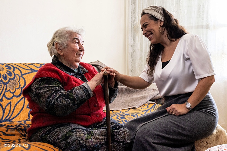 Elderly Jewish woman sitting next to Yael Eckstein and holding her hand