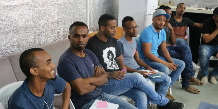 Eight men sitting together having a conversation.
