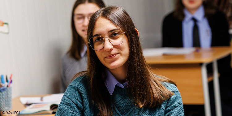 Teenage girl with glasses sitting at a desk