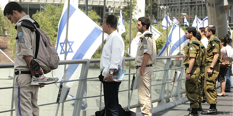 IDF soldiers and pedestrians stand in silence in observance of Yom Hazikaron, Israel’s Memorial Day.