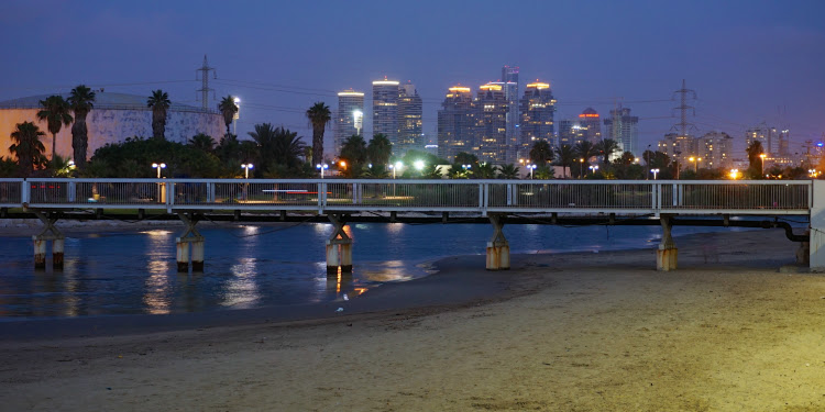 A bridge at night while Tel Aviv is in the distance.