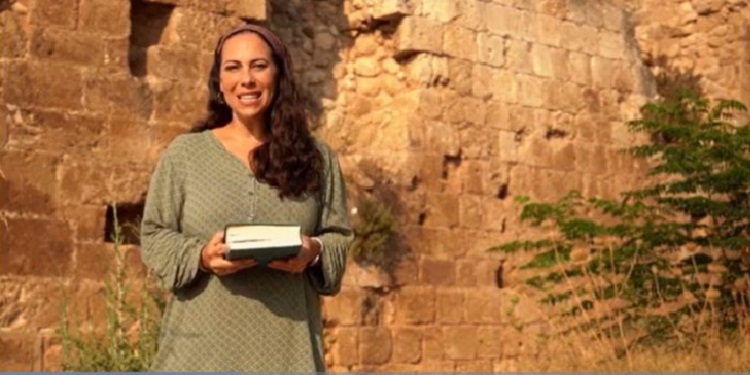 Yael Eckstein in a green dress holding the Bible.