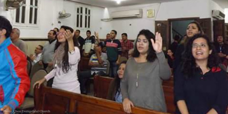 Several raising their hands in praise at a therapeutic camp for Coptic Christians.