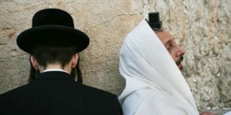Two men praying at the Western Wall beside eachother.