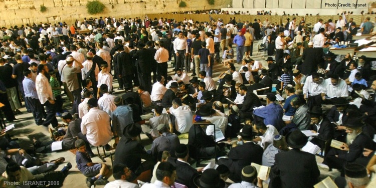 Several people gathering inside a temple while praying, reading the Bible, and talking.