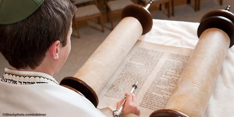 Young boy reading through a torah scroll.