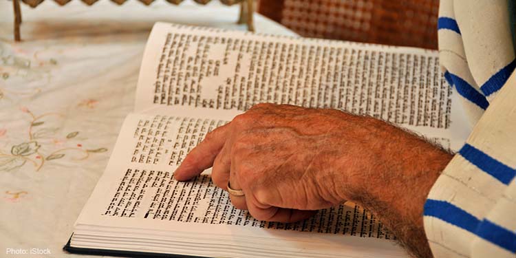 A man is reading the print version of the Jewish Torah (bible)