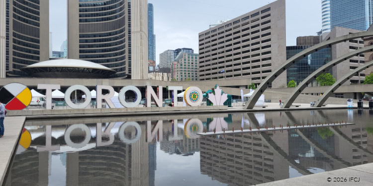 Vibrant Toronto cityscape featuring tall buildings, modern architecture, and a reflective water feature in the foreground, highlighting urban development and vibrant city life.