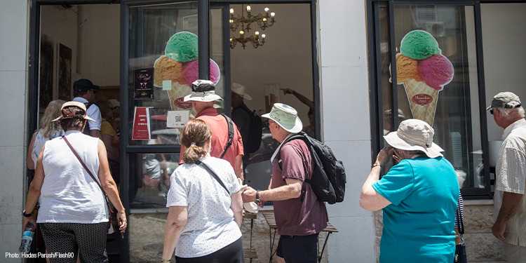 People standing in line outside an ice cream parlor.