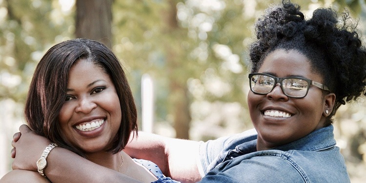 Two women embracing each other and smiling.