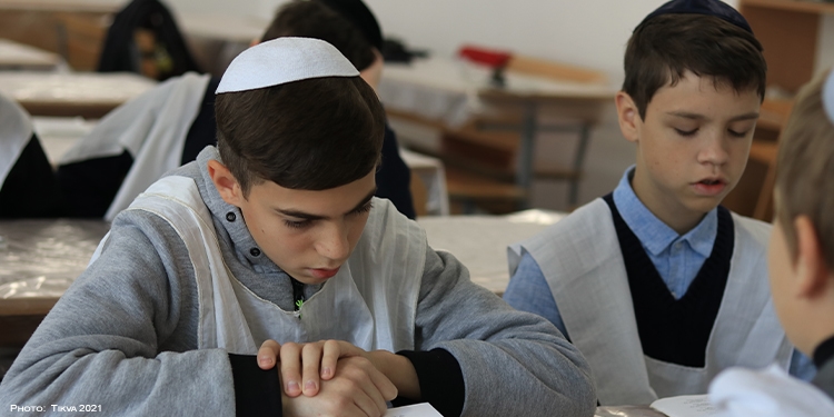 Two boys studying next to one another