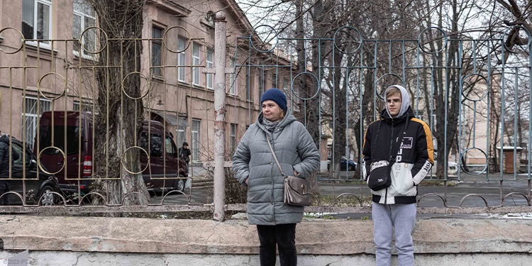 Two people standing with coats on outside in the cold