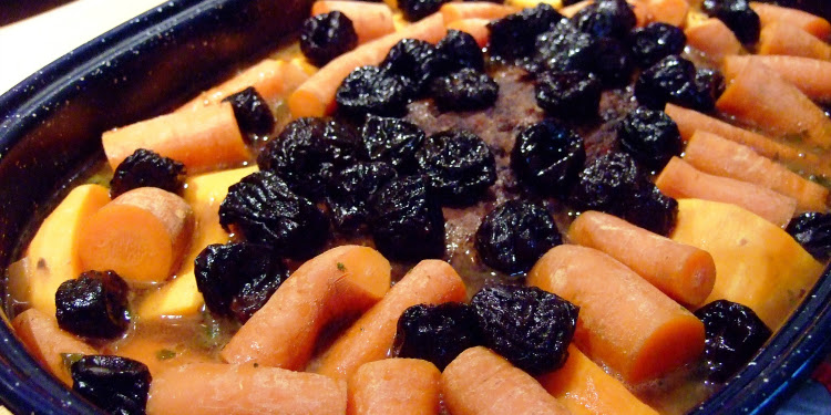 Carrots, raisins, and melon all gathered together in a pan.