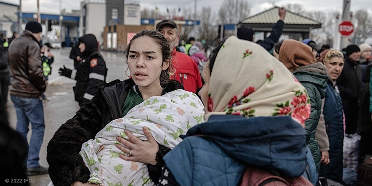 Woman holding her baby while standing next to an elderly Jewish woman.