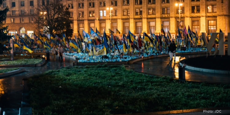 Memorial with numerous Ukrainian flags at night, symbolizing hope and solidarity supported by IFCJ for Ukraine.