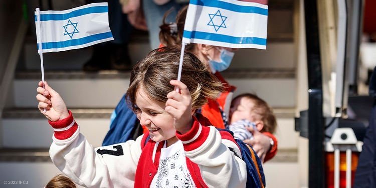 Young girl holding two Israeli flags and celebrating Israel's Independence Day