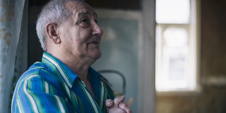 Valery Krasilschik, IFCJ recipient looking up while having his hands in prayer.