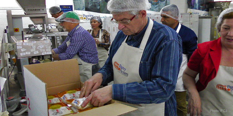 Several volunteers for Pantry Packers in Israel packing food boxes.