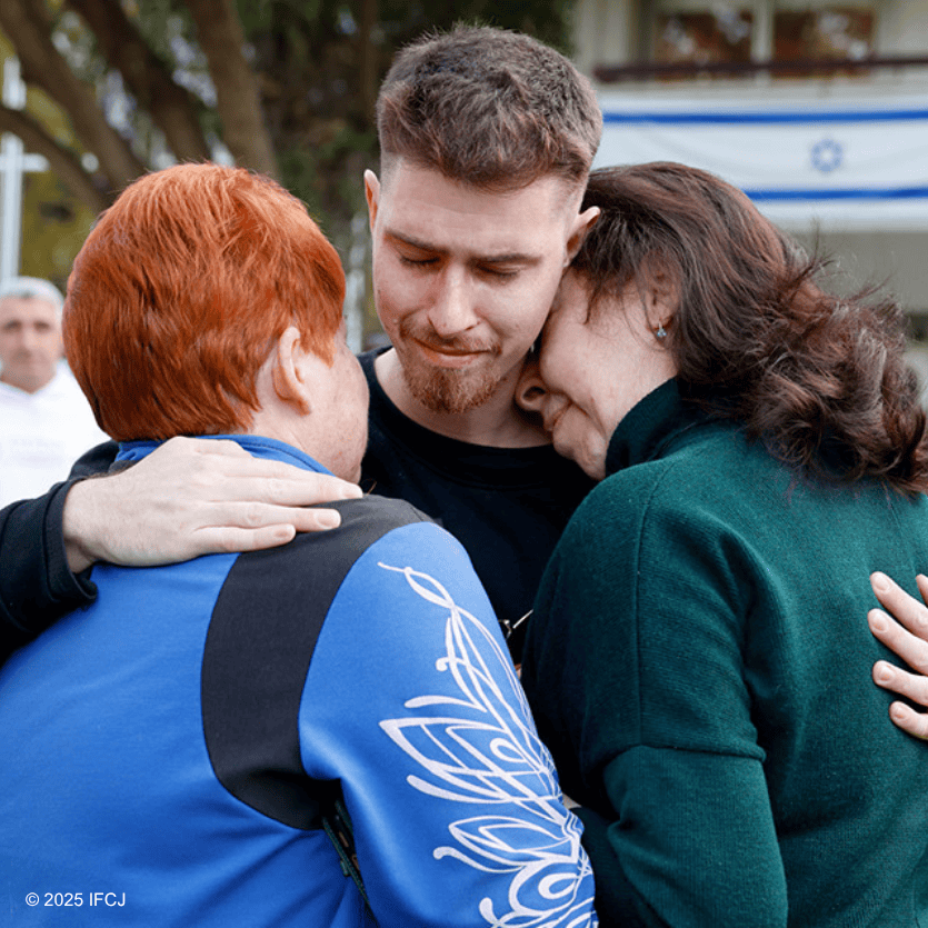 A young man embraces two women in a heartfelt group hug outdoors, symbolizing hope, support, and community connection.