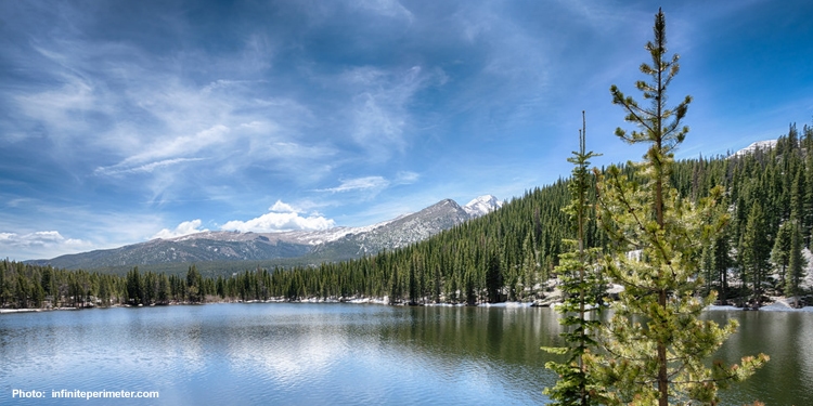 Water, trees, mountains, and a blue sky.