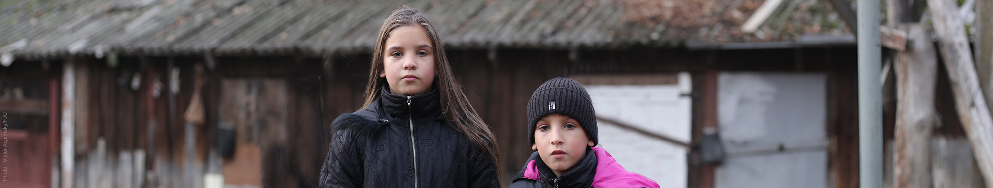 Two young children in black coats looking sad