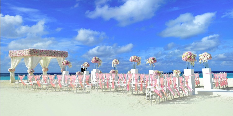 Pink and white wedding set up on a white sand beach.