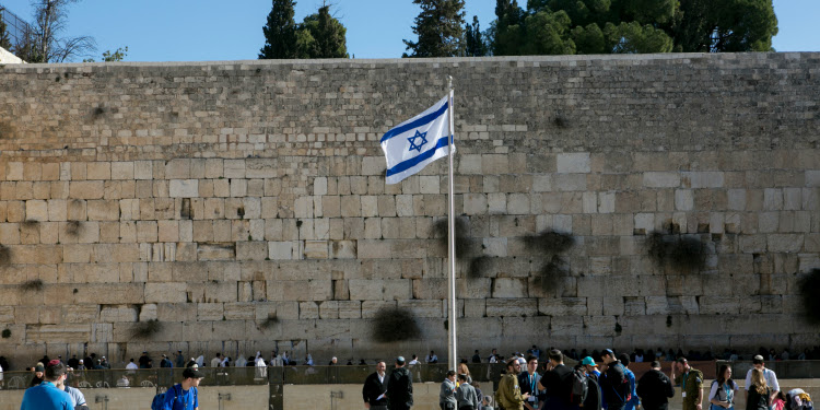 Israeli flag waving in the air in front of the Western Wall.