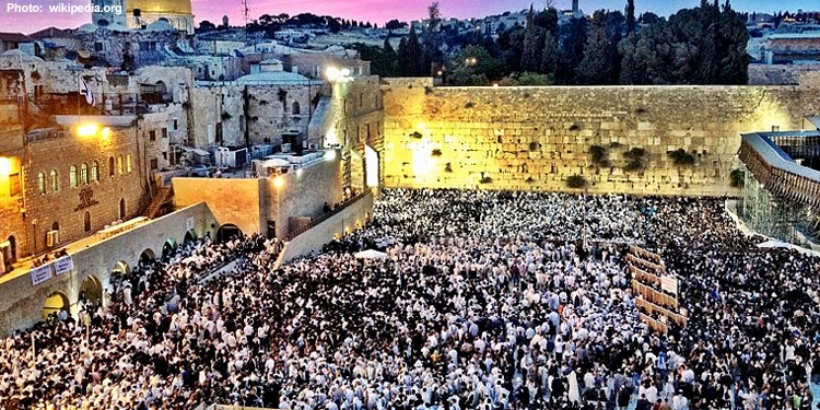 People at the Western Wall while the sun is setting.